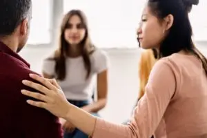 A woman supporting another individual in group therapy.