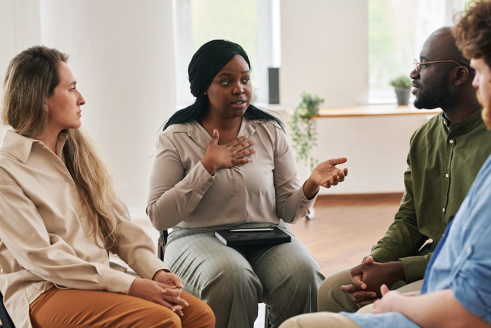 A woman therapist discussing treatment ideas and emphasizing with those in her treatment group.