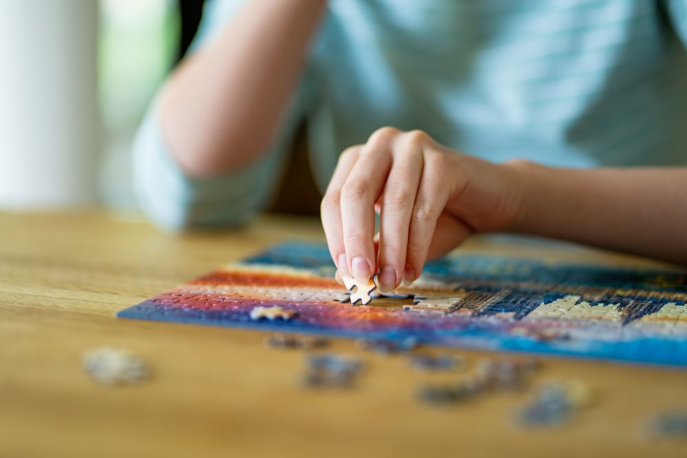 A woman putting together a puzzle to cope with her mental health.