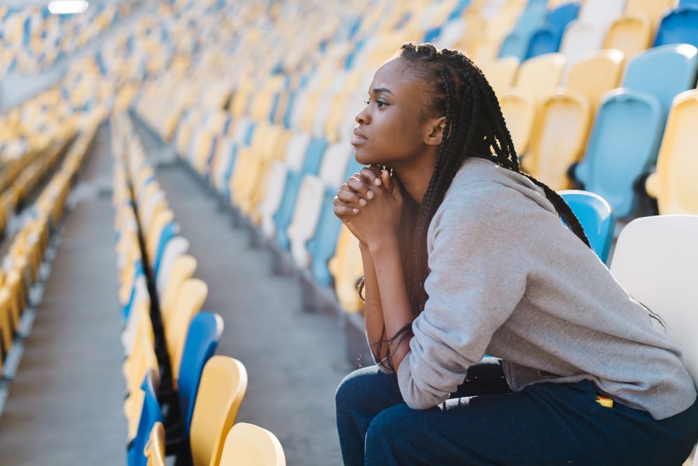 A young woman sitting alone in a stadium contemplating her future.